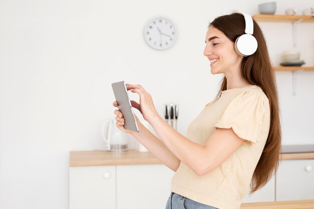 Side view woman with headphones choosing a song from her laptop