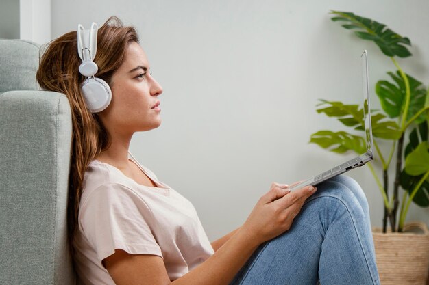 Side view woman with headphones using laptop