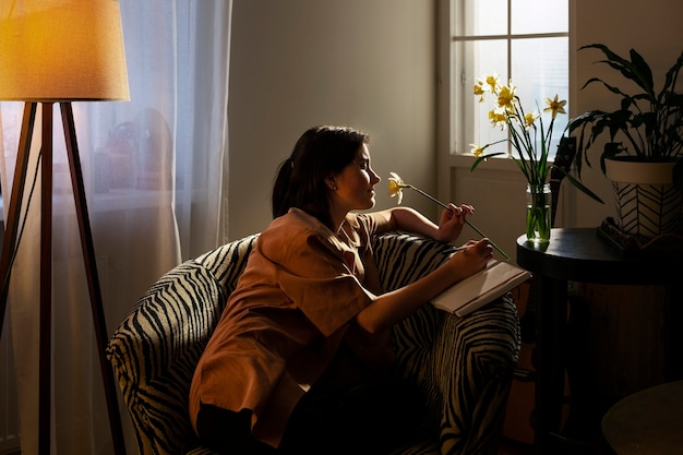 Free photo side view woman with journal at home