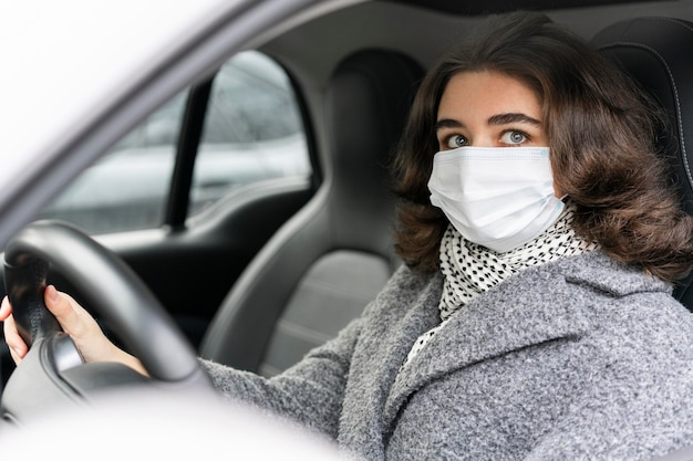 Side view of woman with medical mask driving car