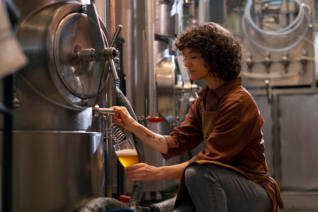 Free photo side view woman working in beer factory