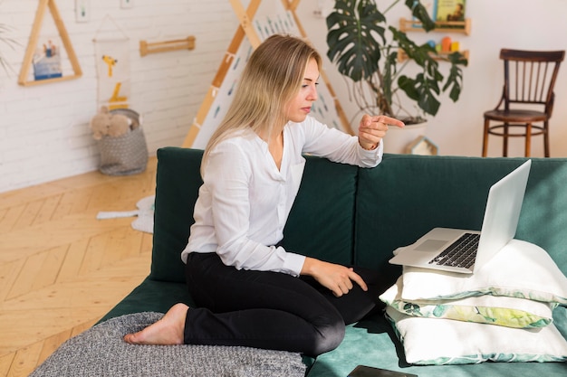 Free photo side view woman working on couch