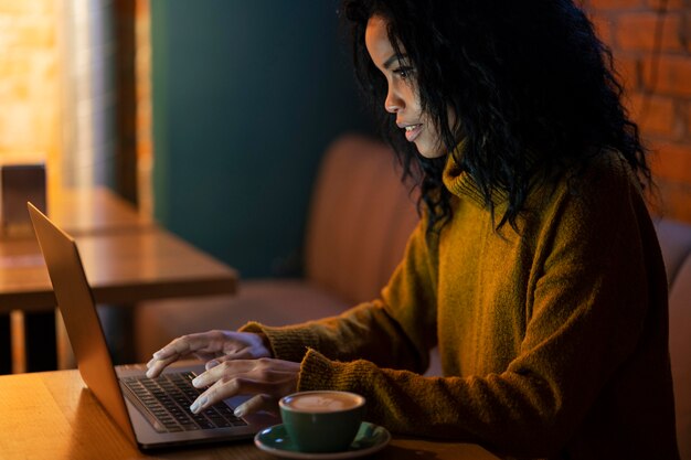 Side view woman working on her laptop in a coffee shop