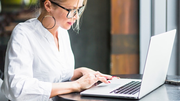 Side view of a woman working on laptop in restaurant