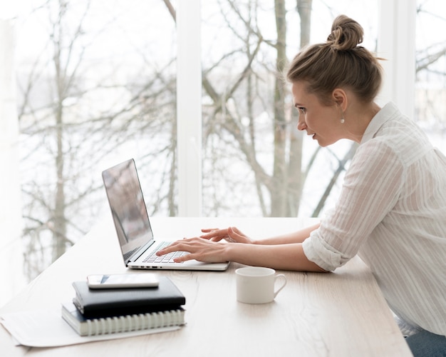 Free photo side view woman working on laptop