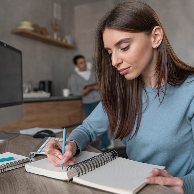 Side view of woman working in the media field writing stuff down on notebook