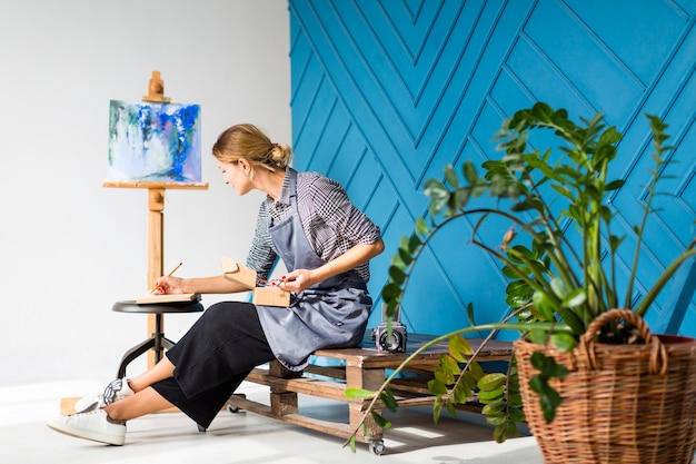 Side view of woman writing and painting