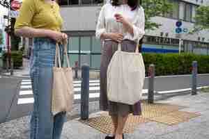 Free photo side view women carrying tote bags