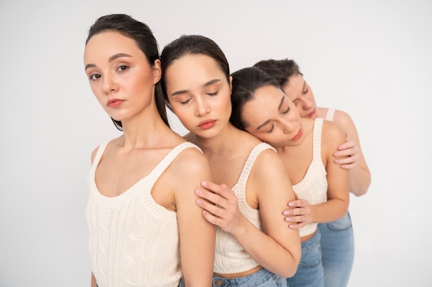 Free photo side view of women in tank tops and jeans posing in minimalist portraits