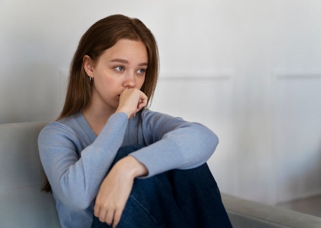 Free photo side view worried woman sitting on couch