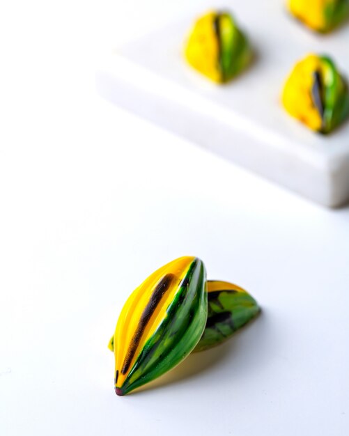 Side view yellow green in black speck chocolate candy on white stand