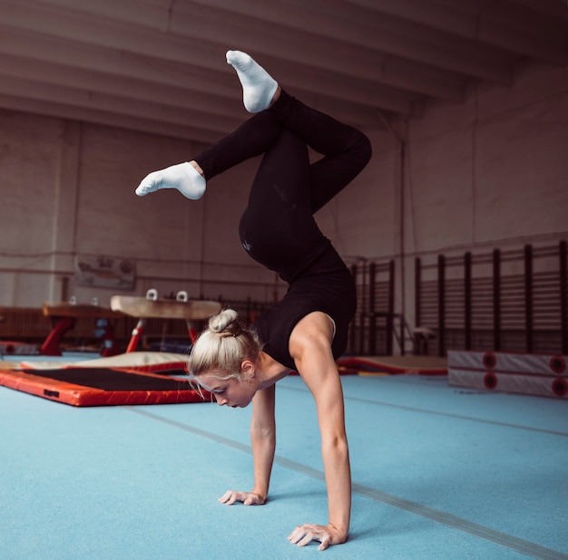 Side view young blonde woman training for gymnastics championship