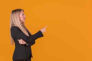 Free photo side view of a young businesswoman pointing his finger against backdrop