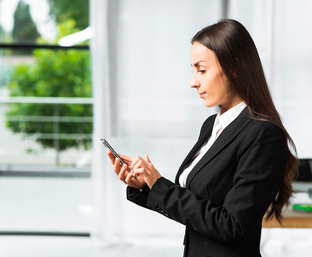 Side view of a young businesswoman using smartphone