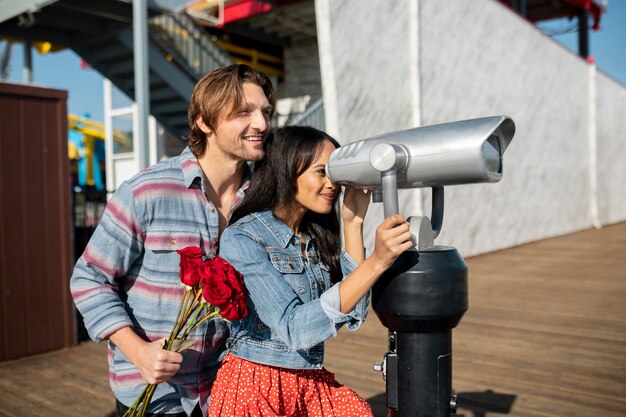 Side view of young couple on a date outdoors looking through telescope