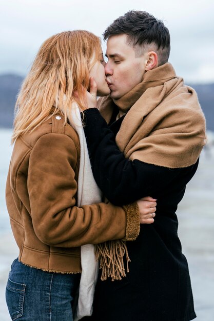 Side view of young couple kissing in winter outdoors