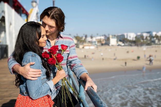 Side view of young couple out on a date at the beach looking over the peer