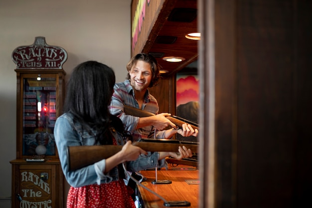 Free photo side view of young couple playing target shooting game while on a date