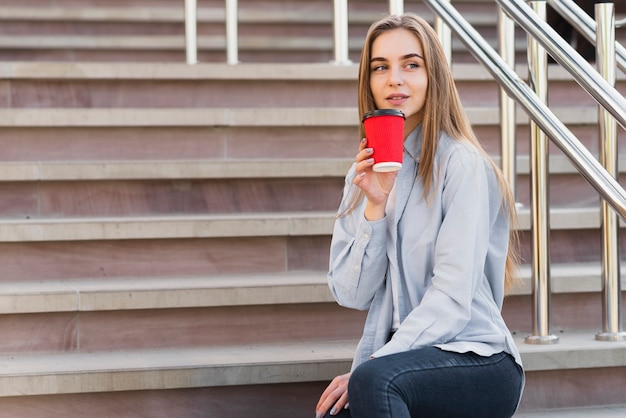 Side view young female drinking coffee outdoor