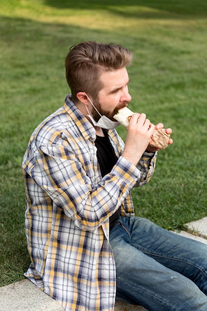 Side view young male eating fast food