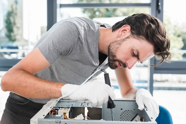 Free photo side view of a young male technician working on broken computer