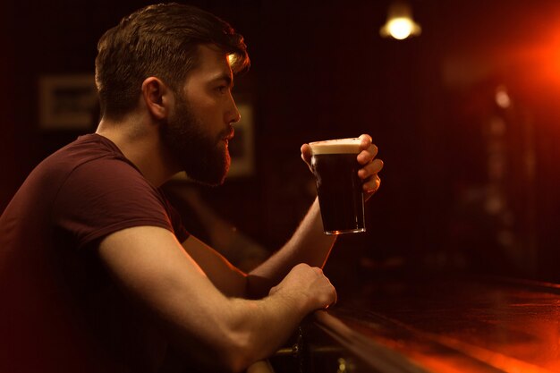 Side view of a young man drinking glass of beer