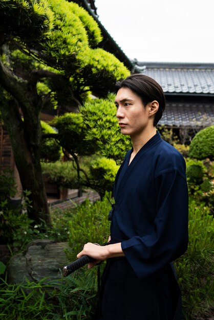 Side view young man holding samurai sword