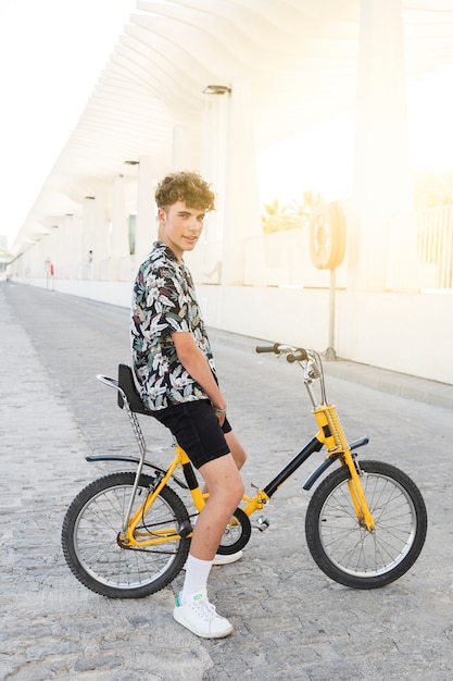 Free photo side view of a young man sitting on bicycle