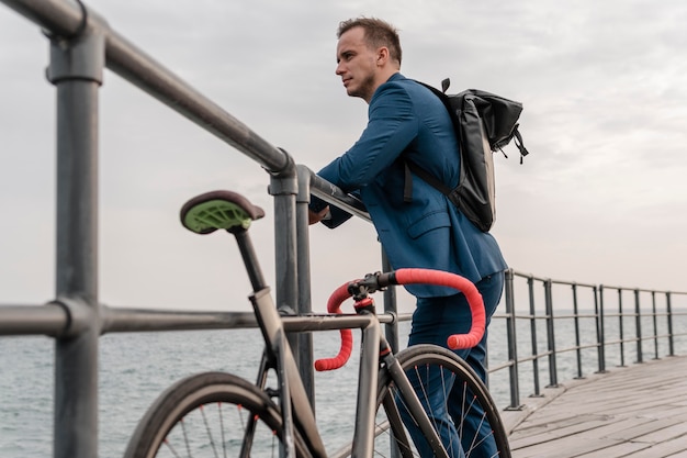 Free photo side view young man standing next to his bike