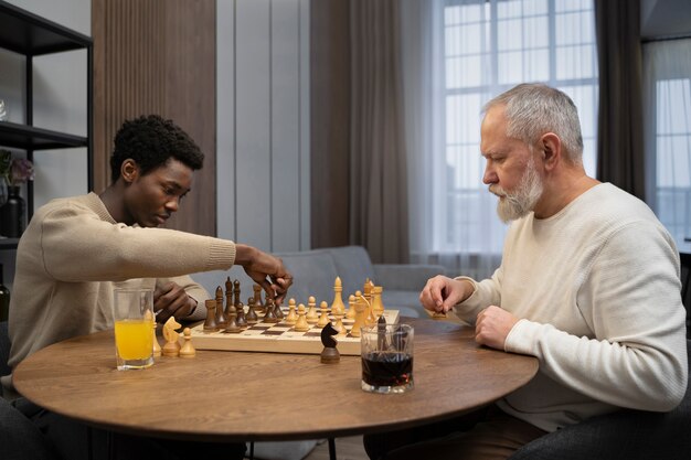 Side view young and old men playing chess