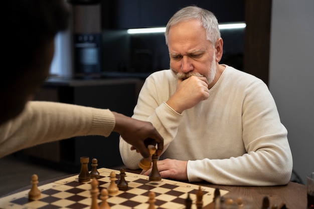 Side view young and old men playing chess