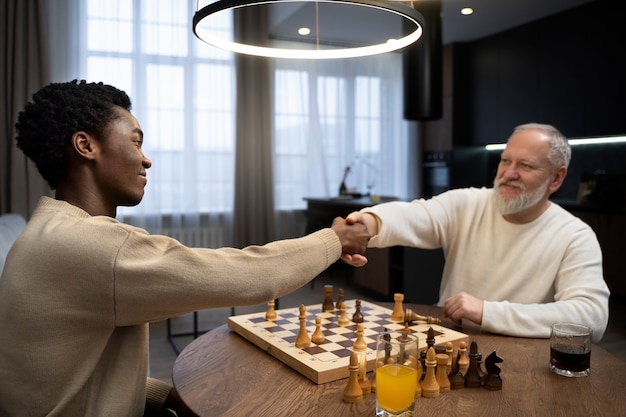 Side view young and old men playing chess