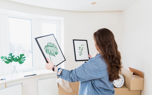 Side view of a young woman choosing picture frame for her new home