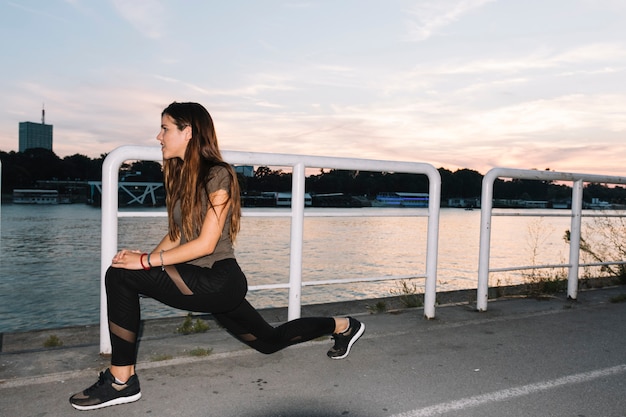 Free photo side view of a young woman exercising on street