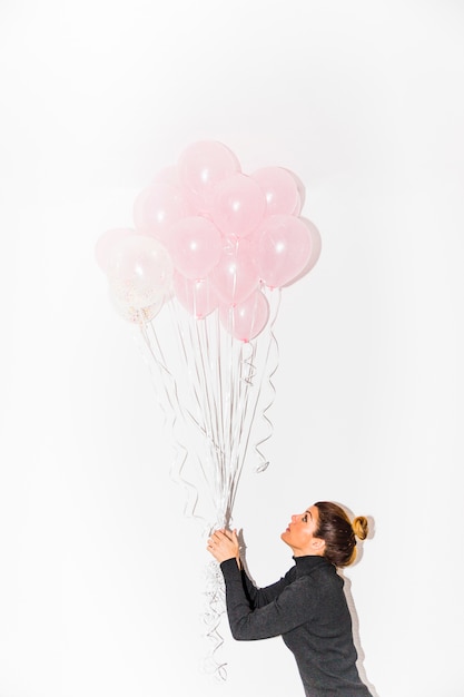 Free photo side view of a young woman holding pink balloons in hand isolated on white background