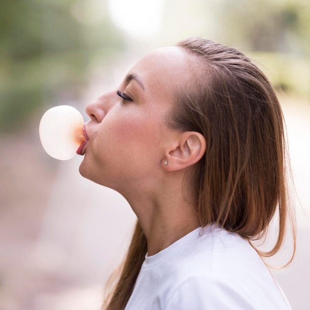 Free photo side view young woman making a gum bubble