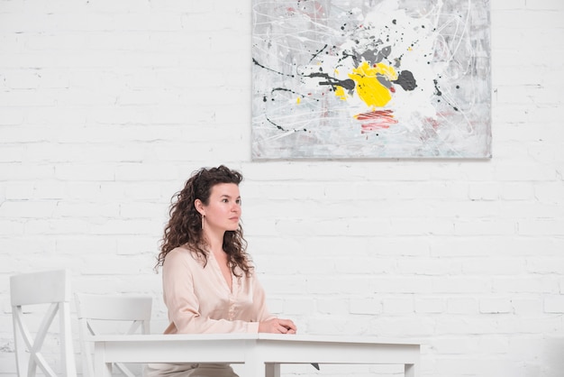 Free photo side view of young woman sitting on dining table