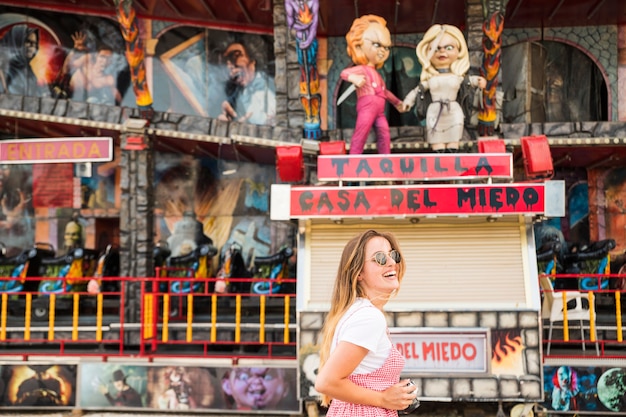 Side view of young woman standing in front of haunted house fun ride