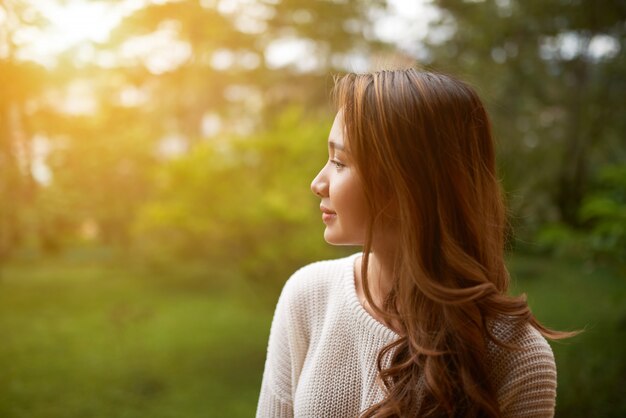 Side waist up shot of woman turning away from camera to look at the sunset