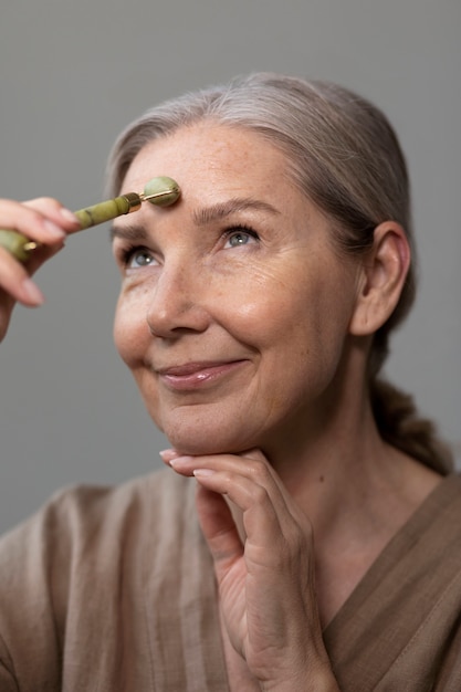 Sided view senior woman massaging face