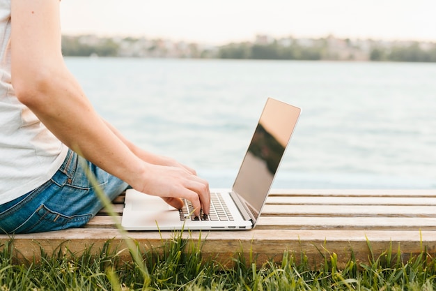 Sideview man using laptop by the water