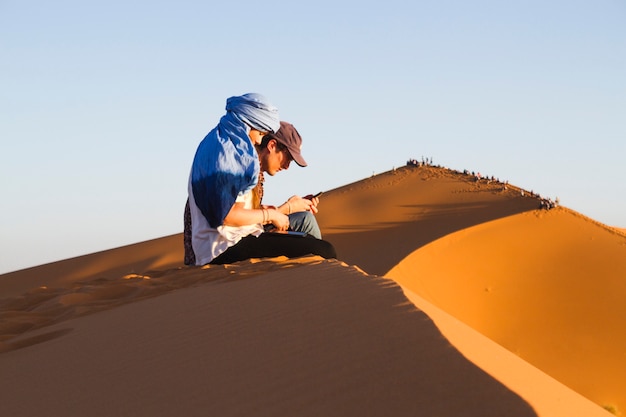 Free Photo sideview of two people sitting on dune 