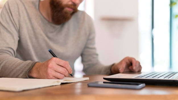 Sideways bearded man taking notes at work