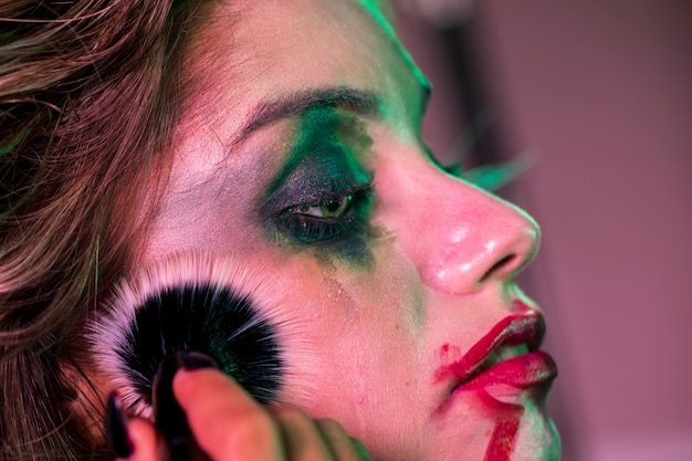 Free photo sideways close-up portrait of a woman using a brush