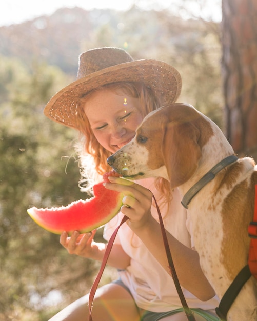 Free Photo sideways dog and woman eating a slice of watermelon