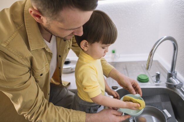 Sideways father and son washing the dishes