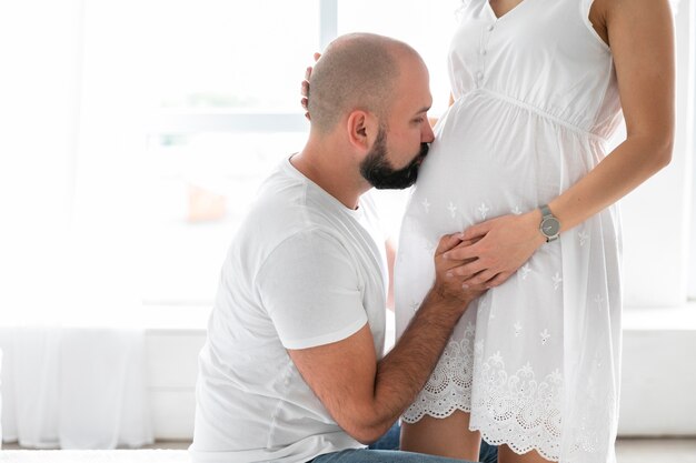 Sideways husband kissing his wife's belly