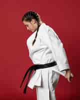 Free photo sideways karate woman in traditional white kimono on red background