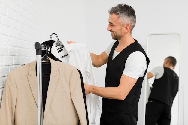 Free Photo sideways man arranging his clothes on the hangers