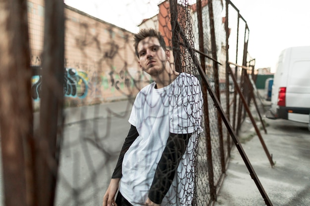 Free photo sideways man leaning against a fence